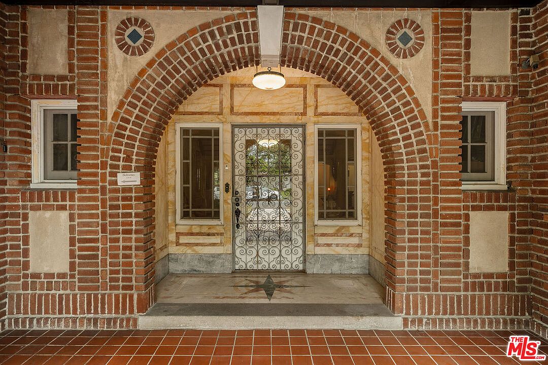 Arched brick entry portico with marble columns and wrought-iron scrollwork door.