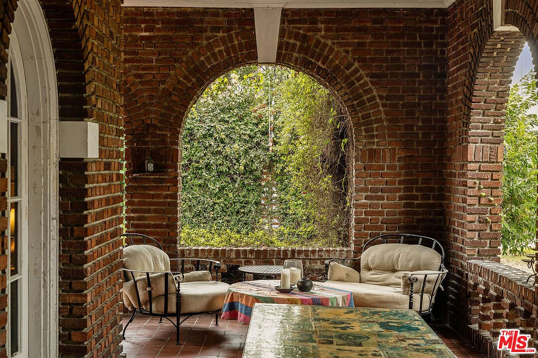 Brick loggia with an arched opening looking out to an ivy-covered wall.